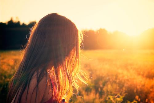 Fotograf&iacute;a de una mujer de perfil contemplando el atardecer en un campo de espigas